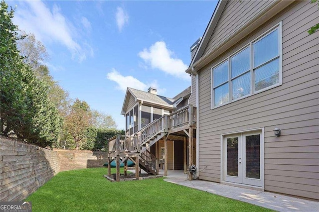 view of yard with a sunroom, a deck, and french doors