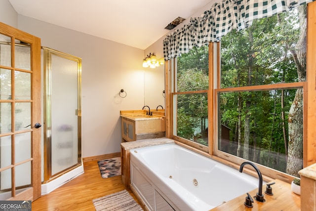 bathroom featuring hardwood / wood-style flooring, vanity, vaulted ceiling, and a tub