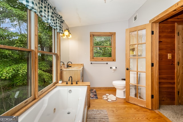 bathroom featuring wood-type flooring, vanity, a bathing tub, toilet, and vaulted ceiling