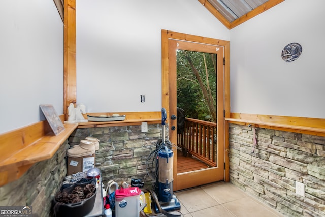 doorway featuring light tile patterned floors and vaulted ceiling