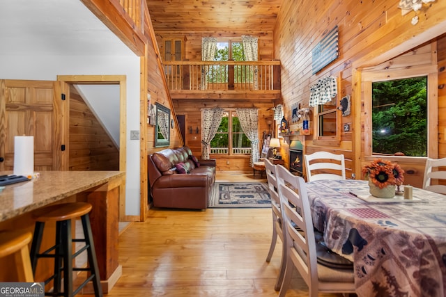 dining room featuring light wood-type flooring, wood walls, lofted ceiling, and wooden ceiling