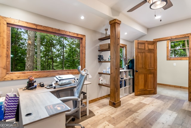 home office with decorative columns, ceiling fan, a healthy amount of sunlight, and light hardwood / wood-style flooring