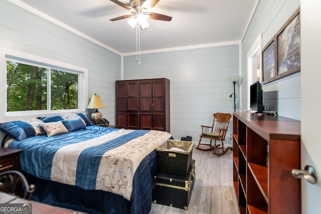 bedroom with ornamental molding, wood walls, ceiling fan, and light hardwood / wood-style flooring