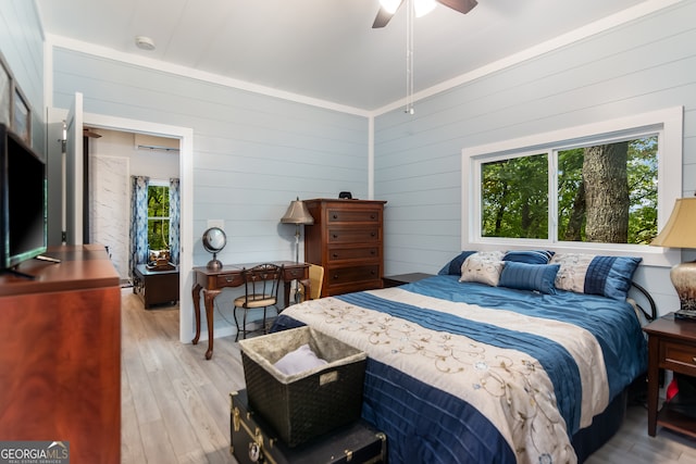 bedroom featuring ceiling fan, wooden walls, and light hardwood / wood-style flooring