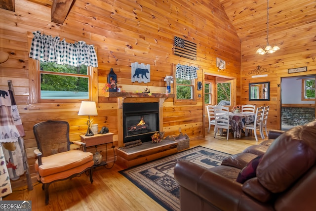 living room featuring high vaulted ceiling, wooden walls, hardwood / wood-style flooring, beamed ceiling, and a chandelier