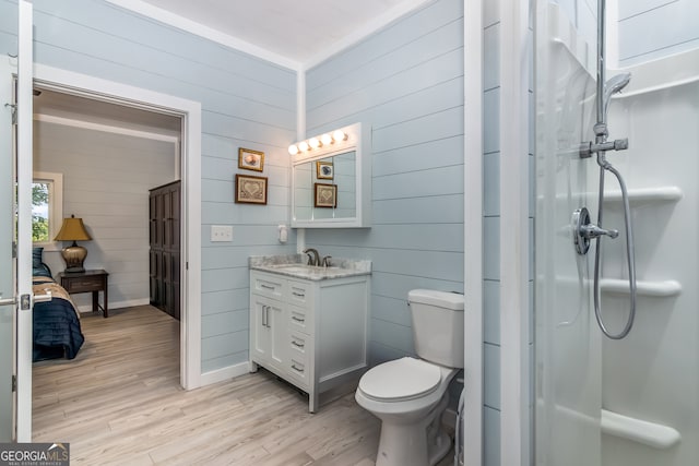 bathroom with wood walls, wood-type flooring, toilet, and vanity