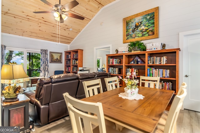 dining room featuring wooden walls, wooden ceiling, high vaulted ceiling, ceiling fan, and light hardwood / wood-style flooring