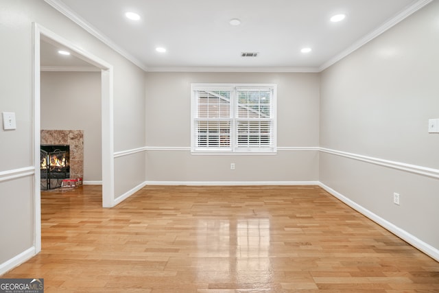 unfurnished room featuring a premium fireplace, light wood-type flooring, and ornamental molding