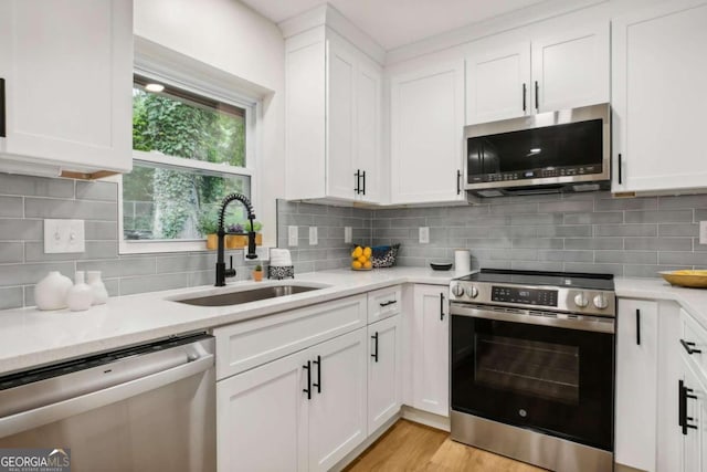 kitchen with stainless steel appliances, white cabinetry, sink, and decorative backsplash