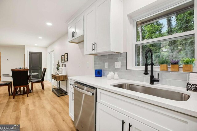 kitchen featuring sink, tasteful backsplash, stainless steel dishwasher, white cabinets, and light wood-type flooring