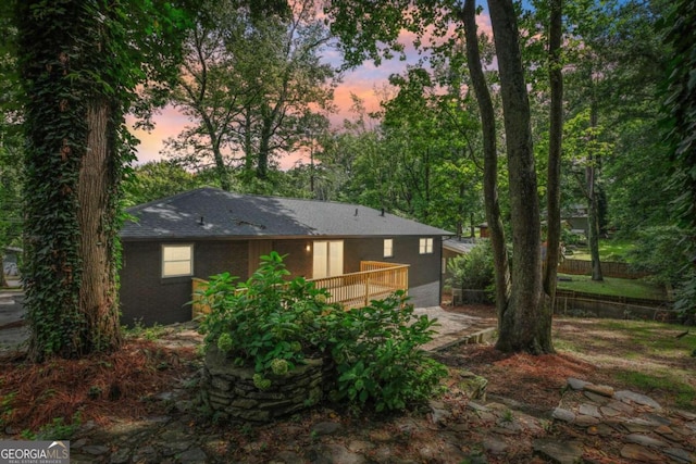 back house at dusk featuring a deck