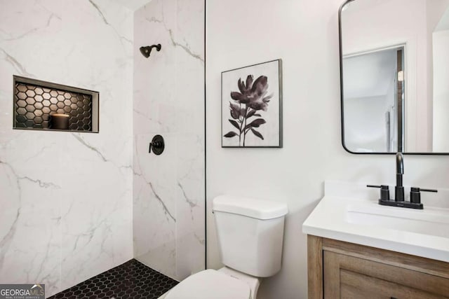 bathroom featuring vanity, toilet, and a tile shower