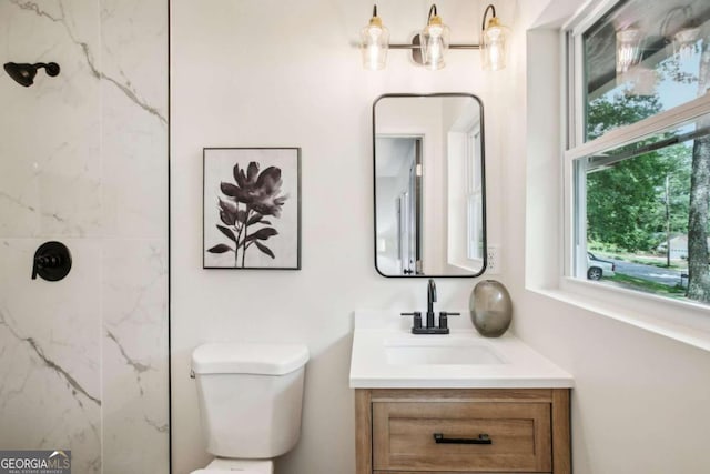 bathroom featuring toilet, vanity, and tiled shower