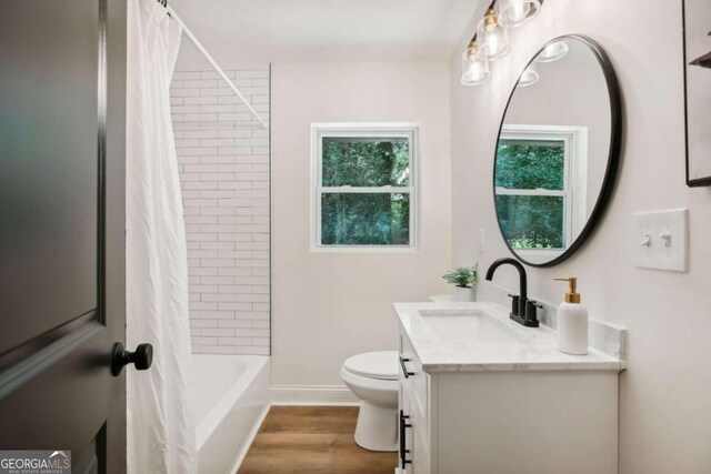 full bathroom featuring hardwood / wood-style floors, shower / tub combo with curtain, vanity, and toilet