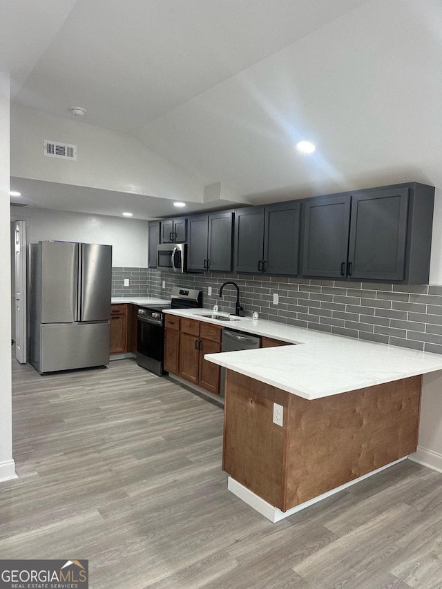 kitchen with kitchen peninsula, appliances with stainless steel finishes, sink, and backsplash