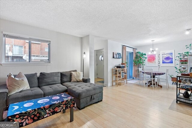 living room featuring a textured ceiling, light wood-type flooring, and a notable chandelier