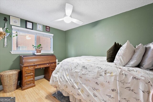 bedroom featuring light hardwood / wood-style floors, ceiling fan, and a textured ceiling