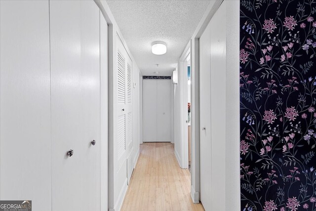 corridor featuring light hardwood / wood-style flooring and a textured ceiling