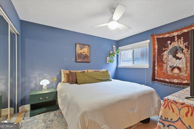 bedroom with a textured ceiling, light hardwood / wood-style floors, ceiling fan, and a closet