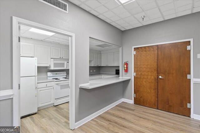 kitchen with white cabinets, white appliances, a paneled ceiling, and light hardwood / wood-style floors