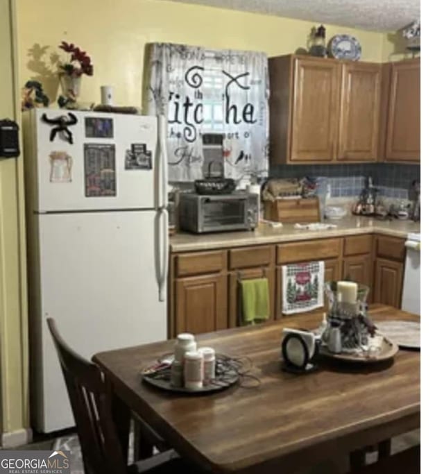 kitchen featuring decorative backsplash, sink, white fridge, and a textured ceiling