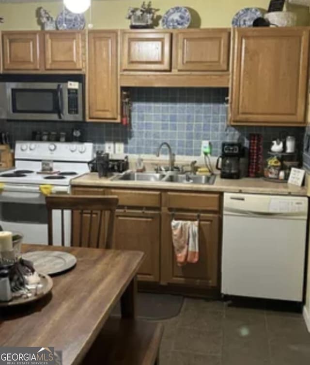 kitchen featuring white appliances, dark tile patterned flooring, sink, and backsplash