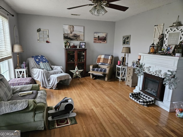 living room featuring hardwood / wood-style floors, a textured ceiling, and ceiling fan