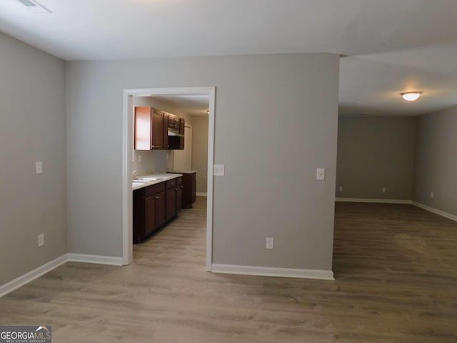 kitchen featuring sink, dark brown cabinetry, and light hardwood / wood-style floors