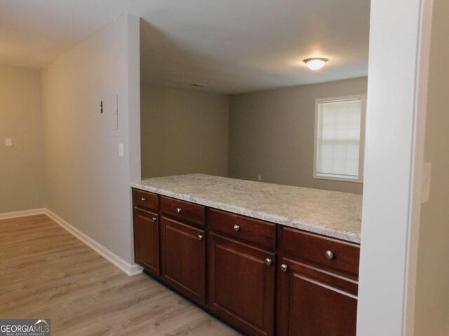 kitchen with kitchen peninsula, dark brown cabinetry, and light hardwood / wood-style floors