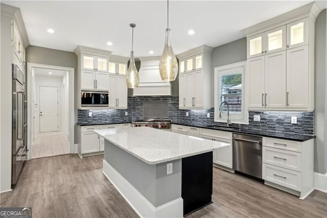 kitchen with white cabinets, light hardwood / wood-style floors, built in appliances, and a kitchen island