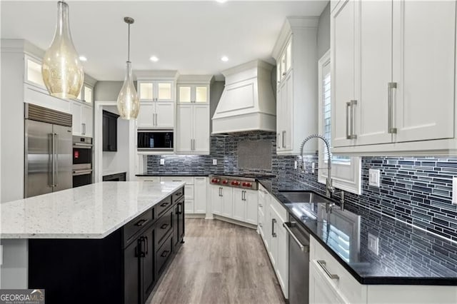 kitchen featuring tasteful backsplash, a center island, custom range hood, white cabinets, and light hardwood / wood-style flooring