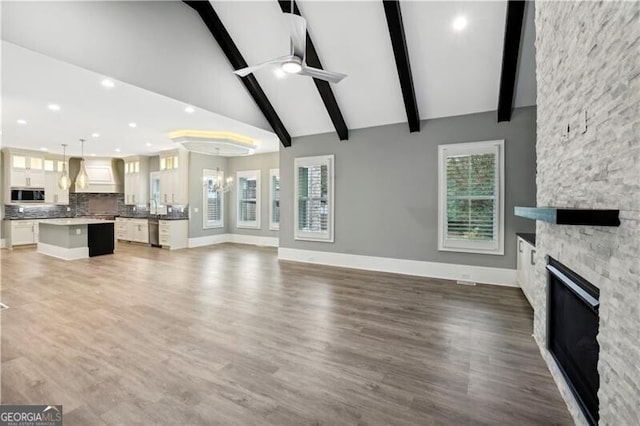 unfurnished living room featuring high vaulted ceiling, ceiling fan with notable chandelier, dark hardwood / wood-style floors, and a fireplace