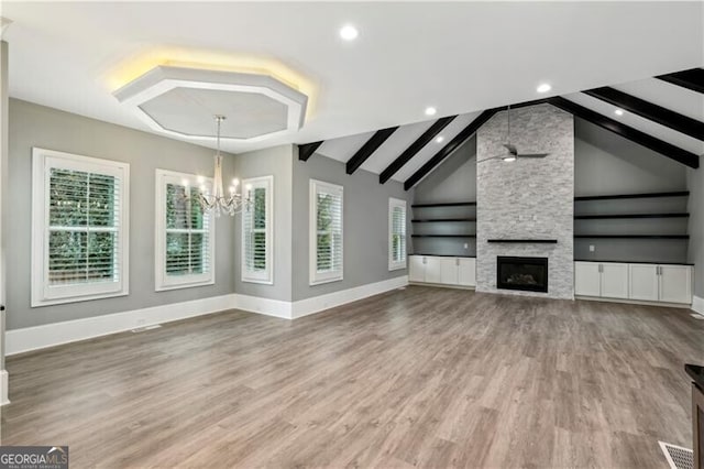 unfurnished living room with a fireplace, ceiling fan with notable chandelier, hardwood / wood-style floors, and vaulted ceiling with beams