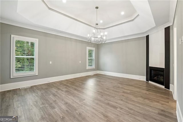 interior space with a tray ceiling, hardwood / wood-style floors, a notable chandelier, and crown molding