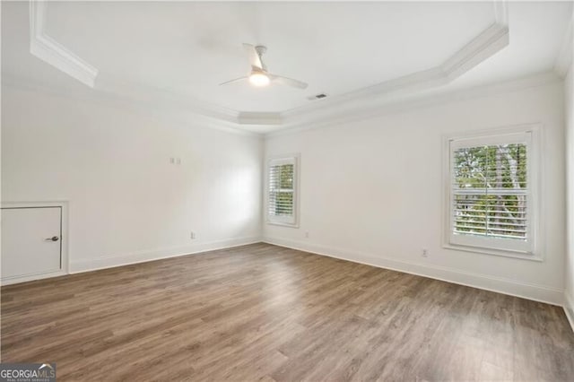 spare room featuring ornamental molding, wood-type flooring, ceiling fan, and a tray ceiling