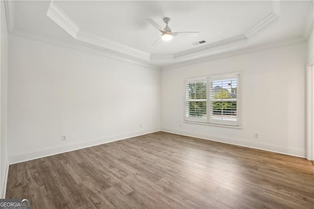 unfurnished room with ceiling fan, ornamental molding, dark hardwood / wood-style flooring, and a tray ceiling