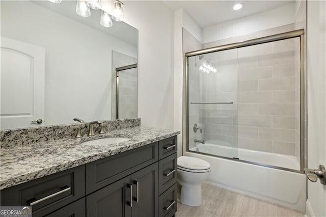 full bathroom with shower / bath combination with glass door, wood-type flooring, vanity, and toilet