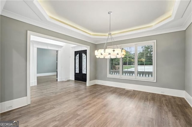 unfurnished dining area with french doors, a notable chandelier, hardwood / wood-style flooring, crown molding, and a tray ceiling