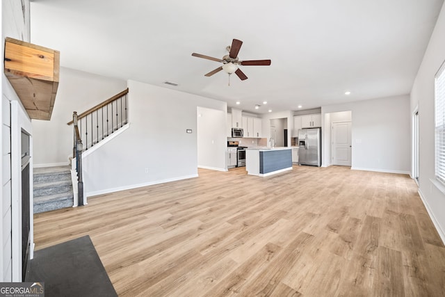 unfurnished living room featuring ceiling fan, light hardwood / wood-style flooring, and sink