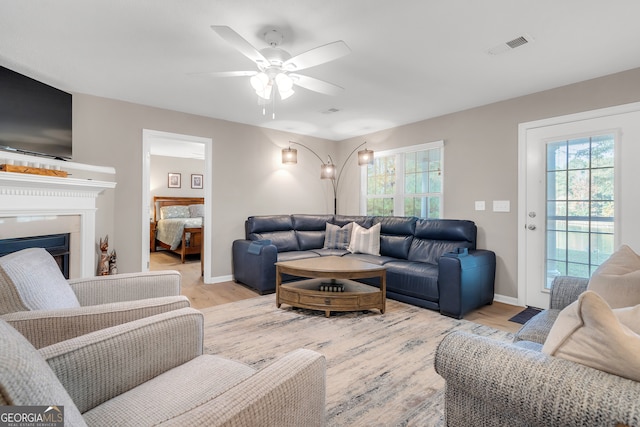 living room featuring ceiling fan, plenty of natural light, and light hardwood / wood-style floors