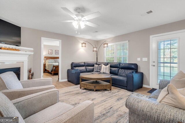 living room with light hardwood / wood-style flooring, plenty of natural light, and ceiling fan