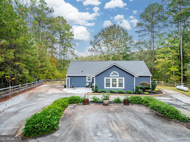 view of front of home with driveway, a shingled roof, and fence