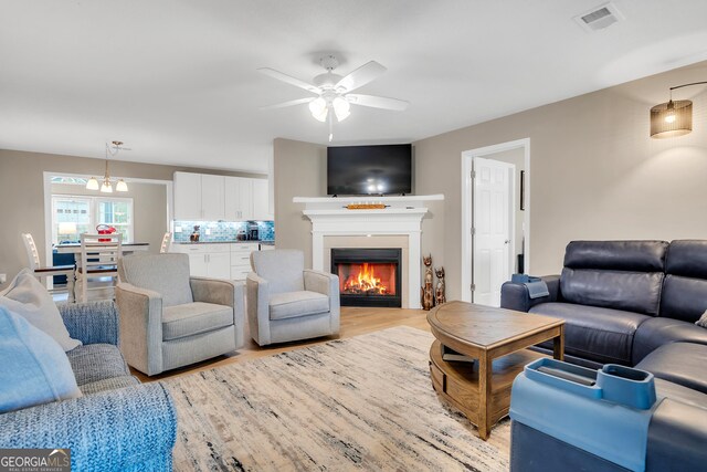 living room featuring ceiling fan with notable chandelier and light hardwood / wood-style flooring