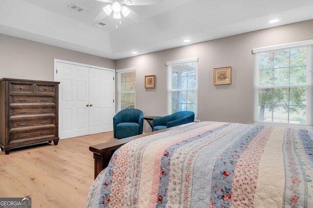 bedroom featuring hardwood / wood-style flooring, ceiling fan, a closet, and multiple windows