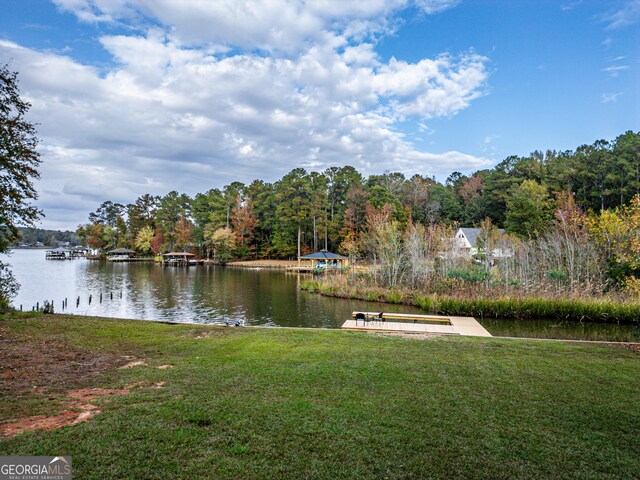 view of dock with a lawn and a water view