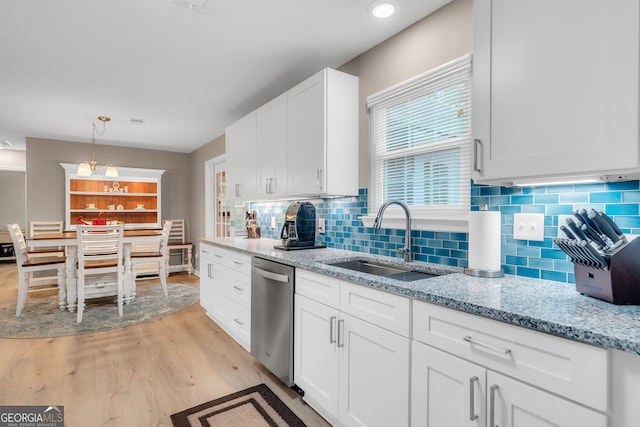 kitchen with light wood-type flooring, stainless steel dishwasher, sink, decorative light fixtures, and white cabinets