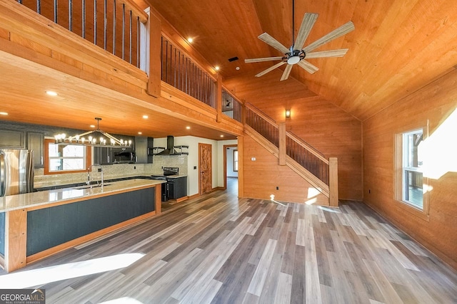 kitchen featuring wood walls, wooden ceiling, dark wood-type flooring, sink, and stainless steel appliances