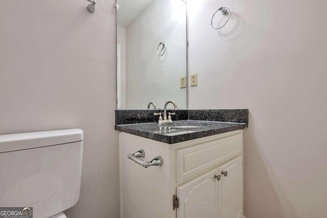 bathroom featuring toilet, vanity, and a textured ceiling