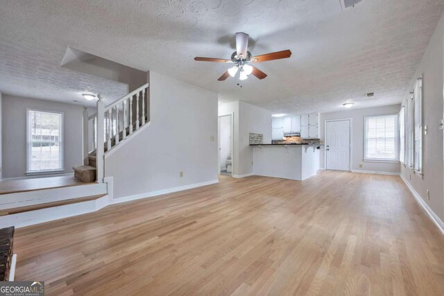 unfurnished living room featuring a textured ceiling, plenty of natural light, and light hardwood / wood-style flooring