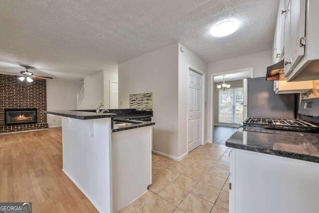 kitchen with white cabinetry, stainless steel appliances, a textured ceiling, and light hardwood / wood-style flooring